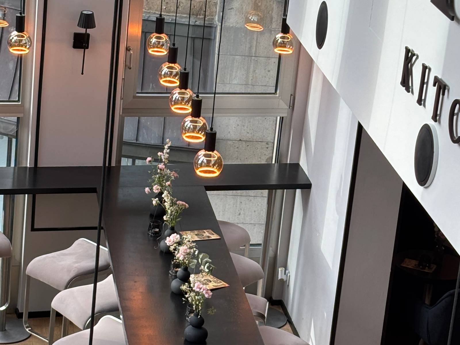 Die Bar des N6 mit Blumen, Glühbirnen und dem Schriftzug Kitchen an der Wand